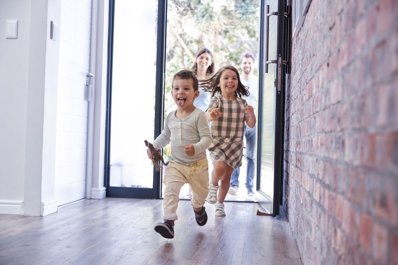 Kinder rennen freudig in ein Haus