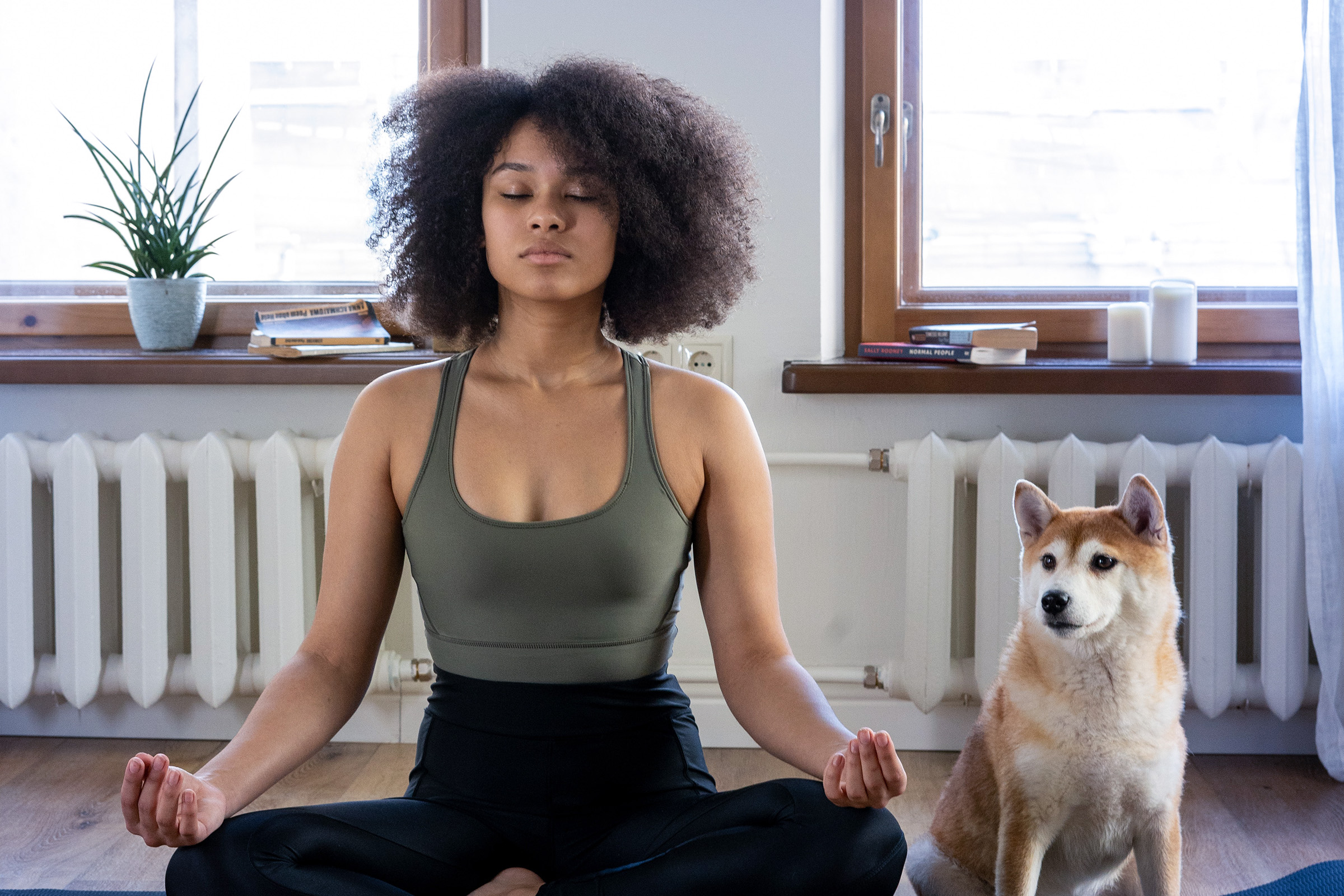 Frau macht Yoga, Hund sitzt daneben